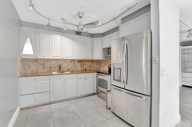 kitchen featuring wood counters, sink, white cabinetry, appliances with stainless steel finishes, and decorative backsplash