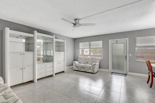 tiled living room featuring ceiling fan and a textured ceiling