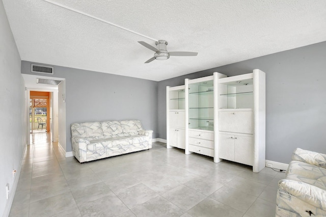 living area featuring ceiling fan and a textured ceiling