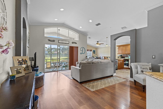 living room with vaulted ceiling, wood-type flooring, ceiling fan, and ornamental molding