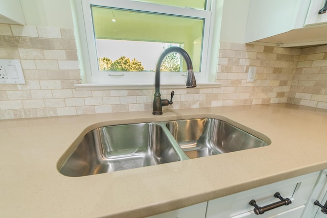 interior details featuring white cabinetry, sink, and decorative backsplash