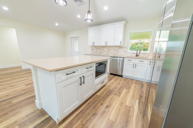 kitchen with white cabinetry, stainless steel appliances, and light wood-type flooring