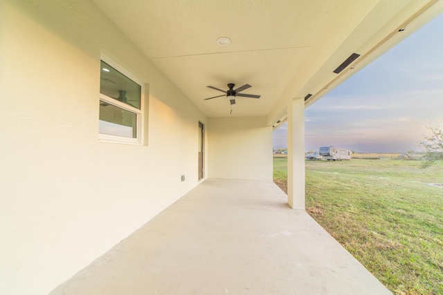 patio terrace at dusk with ceiling fan and a lawn