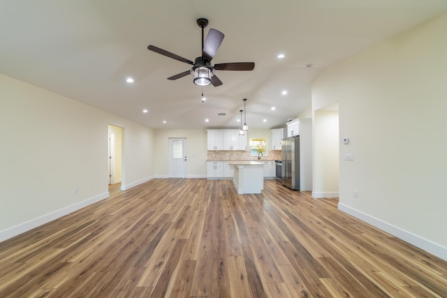 unfurnished living room with vaulted ceiling, light hardwood / wood-style floors, and ceiling fan