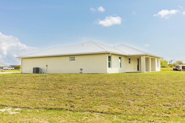 rear view of property with central AC unit and a yard