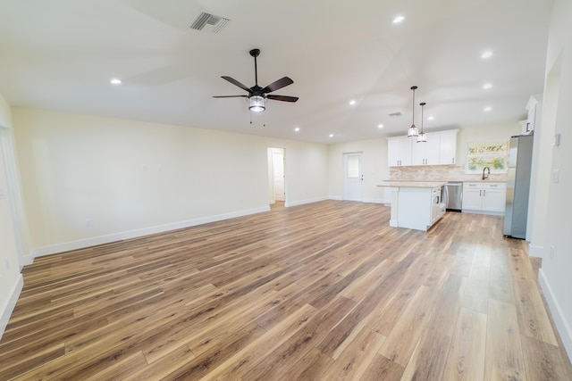 unfurnished living room with lofted ceiling, sink, light hardwood / wood-style floors, and ceiling fan