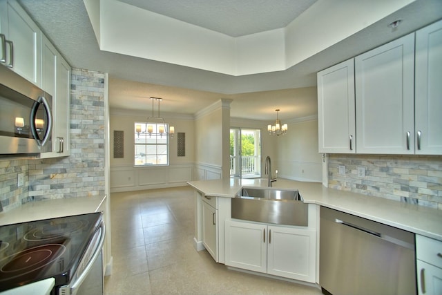 kitchen featuring a notable chandelier, light countertops, appliances with stainless steel finishes, wainscoting, and a sink