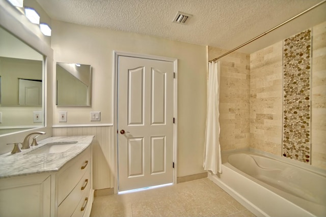 bathroom featuring a wainscoted wall, a textured ceiling, shower / bath combination with curtain, and visible vents