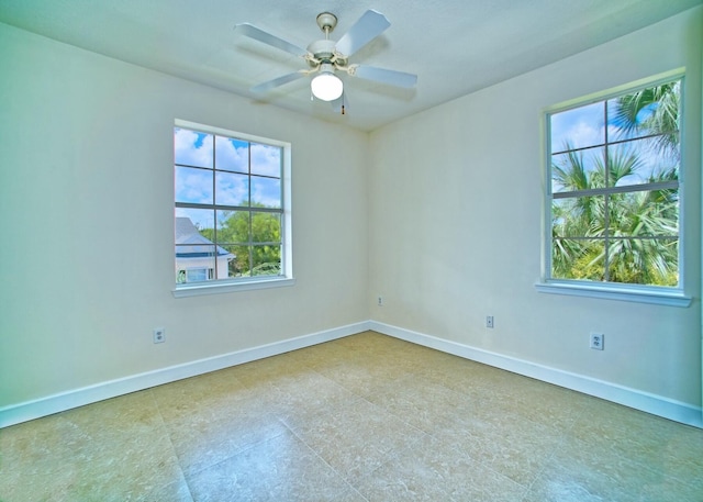 empty room with ceiling fan and baseboards