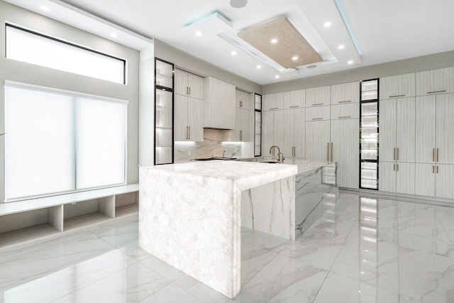 kitchen with light stone counters, a kitchen bar, sink, and a kitchen island