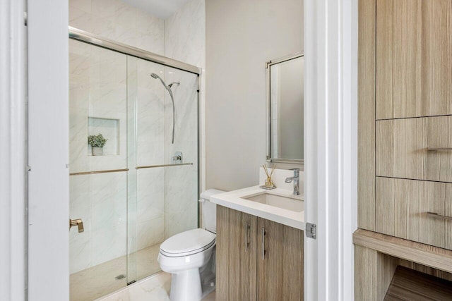 bathroom with a shower with door, vanity, and toilet