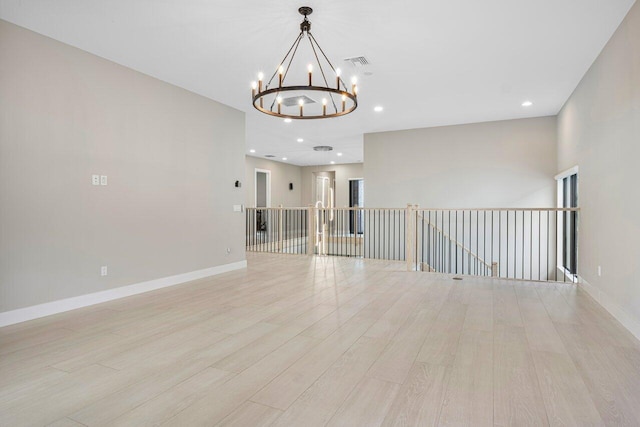 empty room featuring an inviting chandelier and light hardwood / wood-style floors