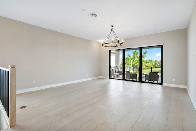 spare room featuring an inviting chandelier and light hardwood / wood-style flooring