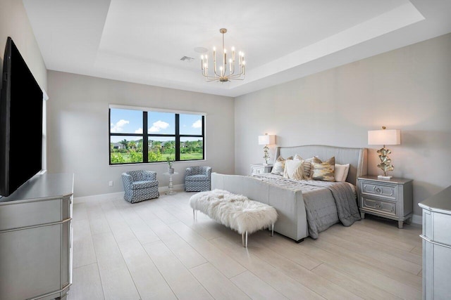 bedroom featuring a chandelier, a raised ceiling, and light hardwood / wood-style floors