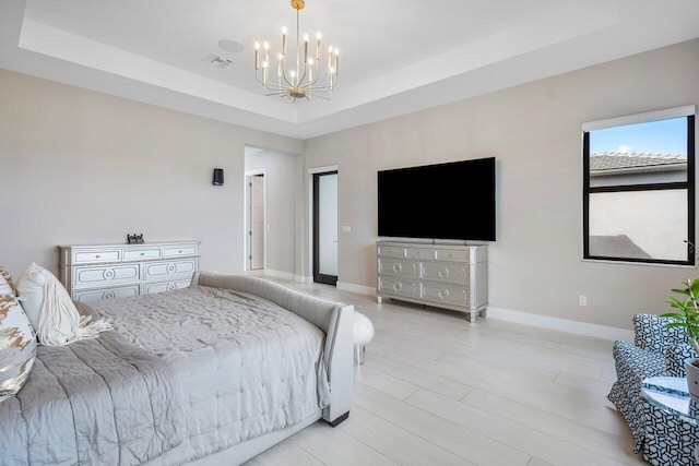 bedroom featuring a tray ceiling, light hardwood / wood-style floors, and a chandelier