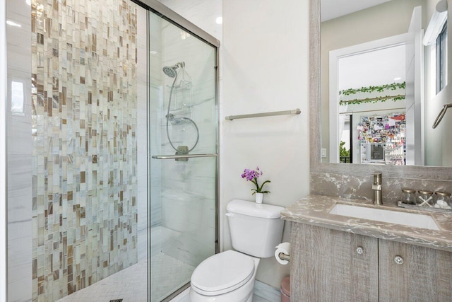 bathroom featuring vanity, a shower with shower door, and toilet