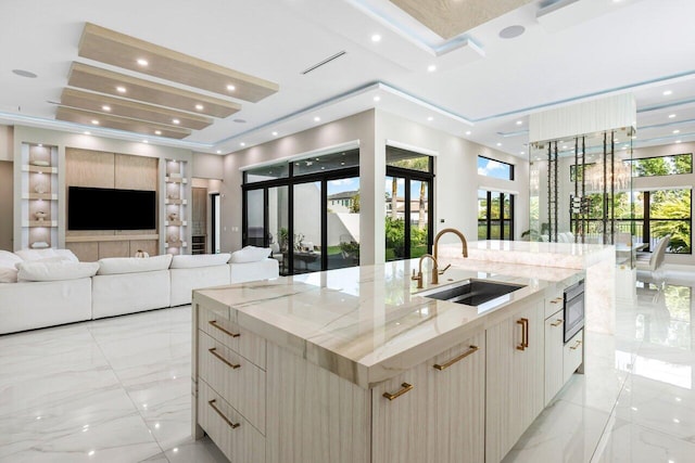 kitchen featuring built in microwave, sink, light brown cabinets, a large island, and light stone countertops