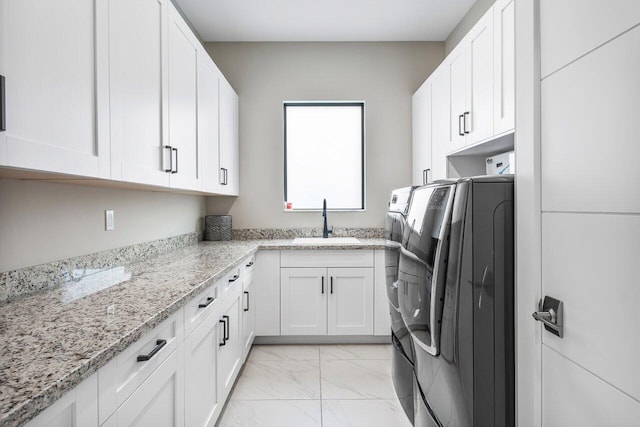 washroom featuring sink, washing machine and dryer, and cabinets