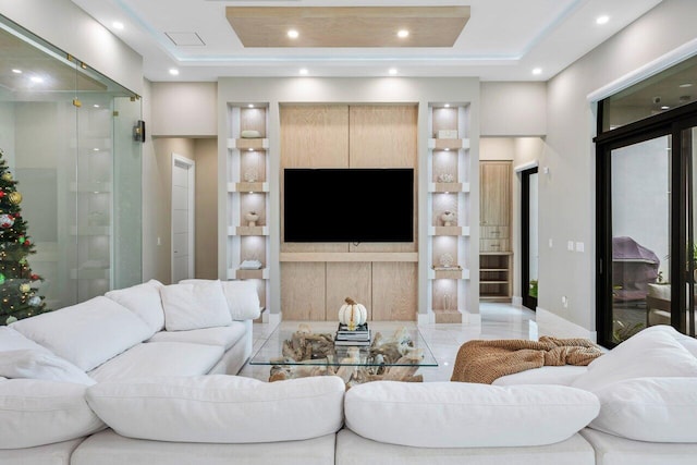 living room with built in shelves and a tray ceiling