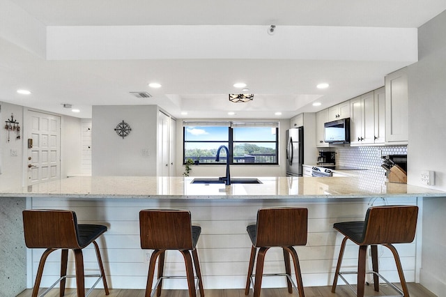 kitchen with white cabinetry, sink, a breakfast bar area, and kitchen peninsula