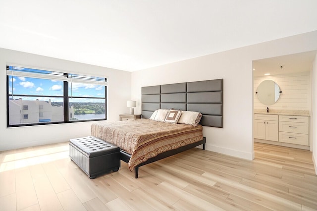 bedroom featuring connected bathroom and light hardwood / wood-style flooring