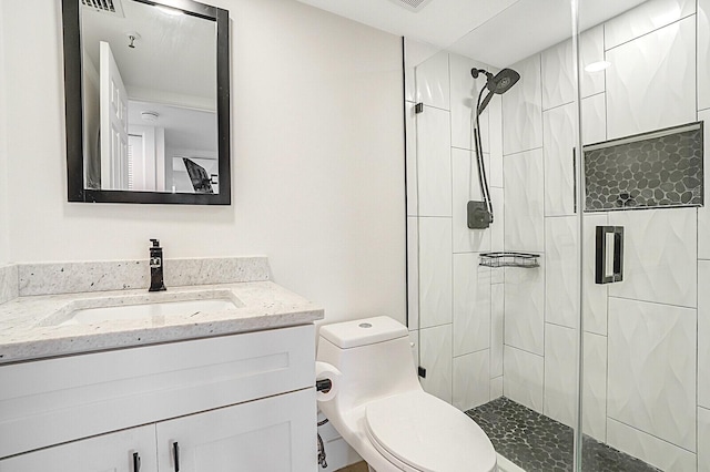 bathroom featuring vanity, a shower with shower door, and toilet