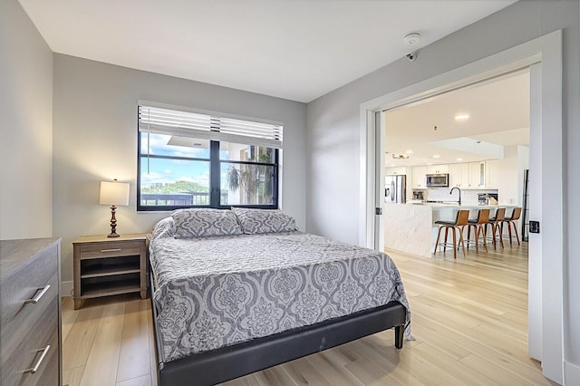 bedroom with sink, stainless steel fridge with ice dispenser, and light hardwood / wood-style flooring