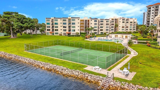 view of sport court featuring a water view and a yard