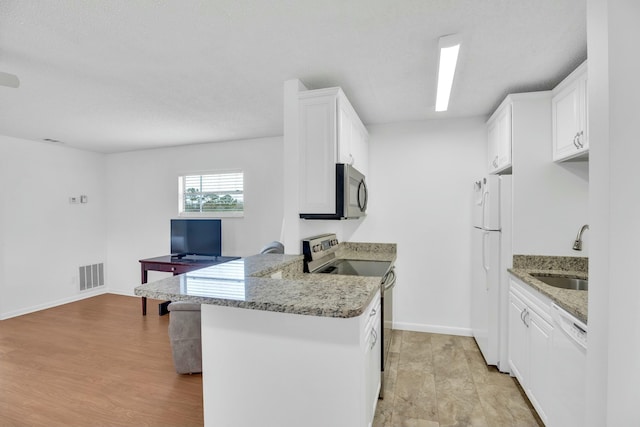 kitchen with stainless steel appliances, white cabinetry, sink, and kitchen peninsula