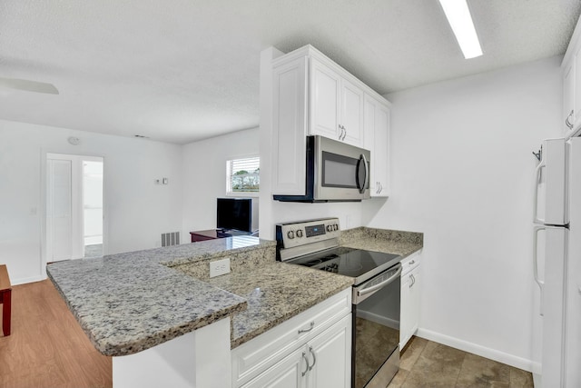 kitchen featuring white cabinetry, stainless steel appliances, kitchen peninsula, and light stone counters