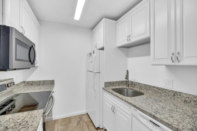 kitchen with white cabinetry, sink, light stone counters, light hardwood / wood-style floors, and stainless steel appliances