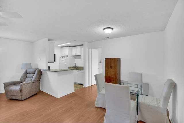 dining area with light hardwood / wood-style floors and a textured ceiling