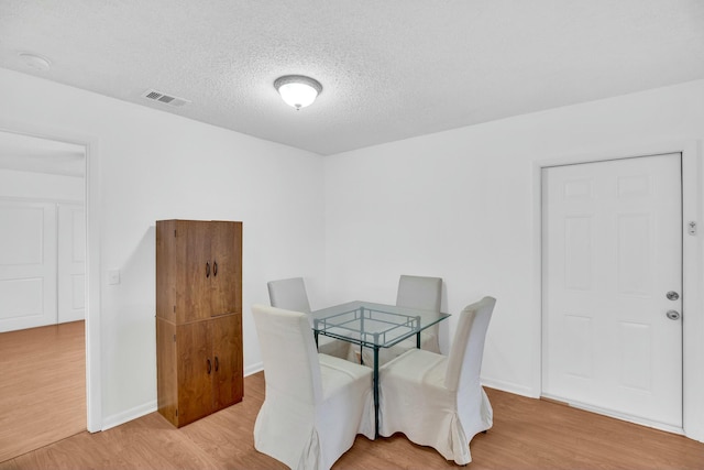 dining space featuring a textured ceiling and light wood-type flooring