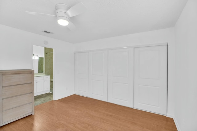 unfurnished bedroom featuring ceiling fan, a closet, connected bathroom, and light hardwood / wood-style flooring