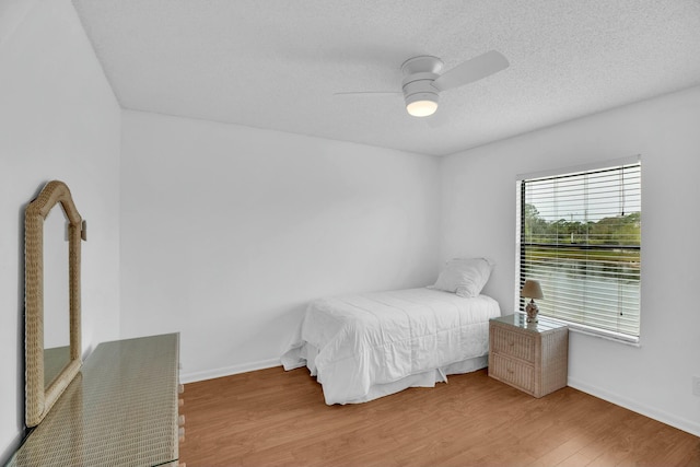 bedroom with hardwood / wood-style flooring, ceiling fan, and a textured ceiling