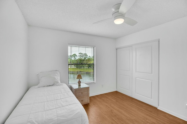 bedroom with hardwood / wood-style flooring, ceiling fan, a textured ceiling, and a closet