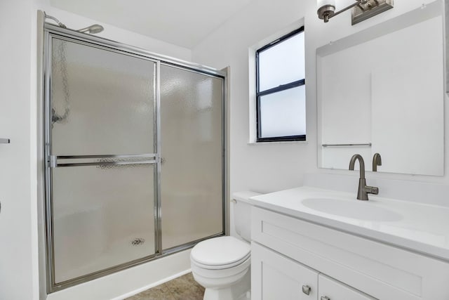 bathroom featuring vanity, a shower with shower door, and toilet