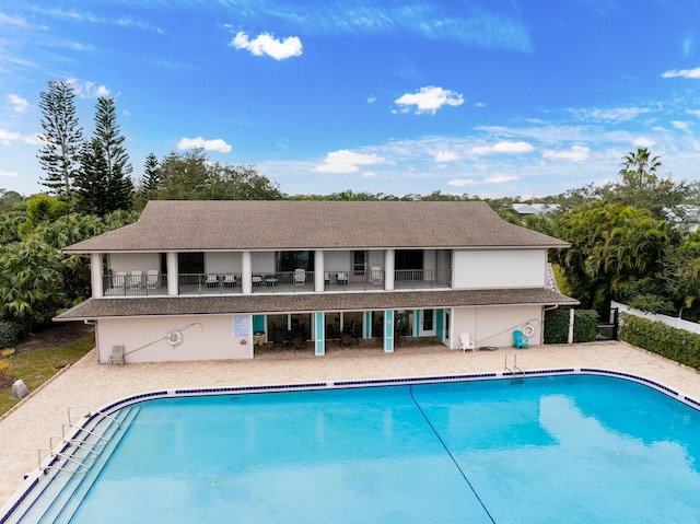 rear view of property with a community pool and a patio area