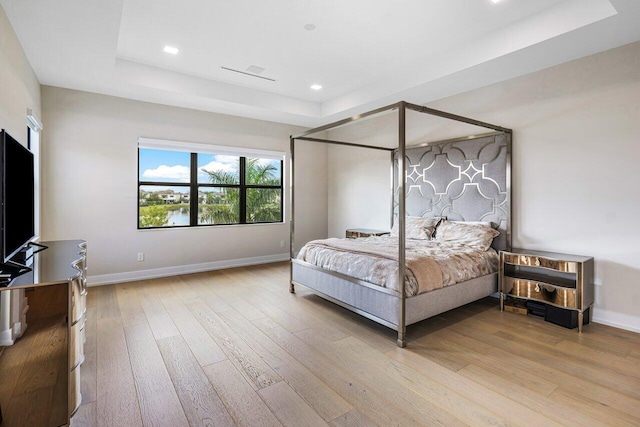 bedroom featuring a tray ceiling and light wood-type flooring