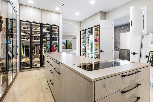 kitchen with black electric stovetop, light wood-type flooring, and a kitchen island