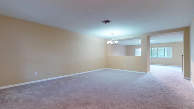 carpeted spare room with ceiling fan with notable chandelier