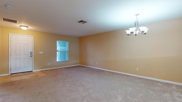 unfurnished room featuring a notable chandelier, baseboards, visible vents, and light colored carpet