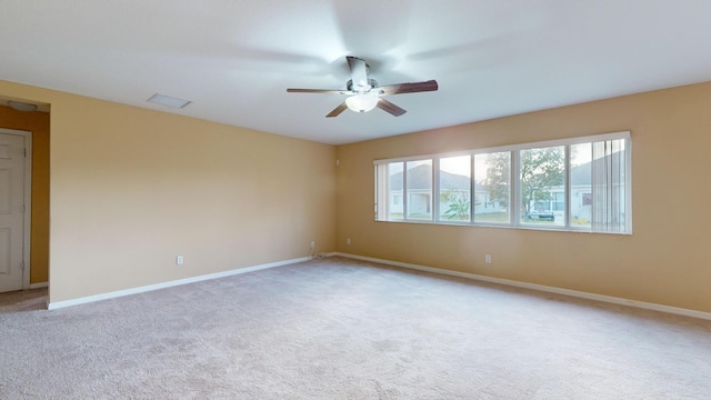 unfurnished room with a ceiling fan, light carpet, and baseboards