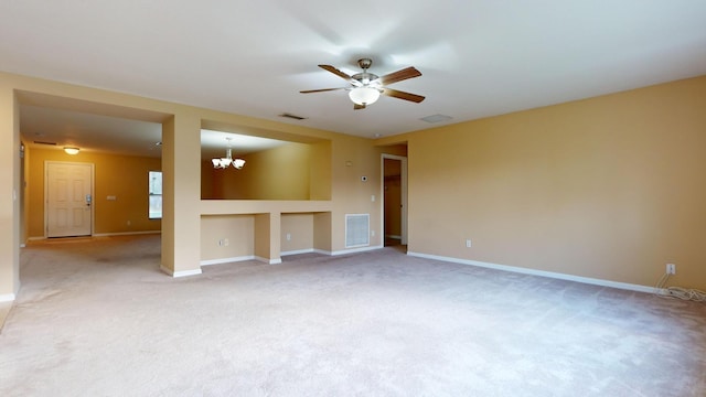 carpeted spare room with ceiling fan with notable chandelier, visible vents, and baseboards