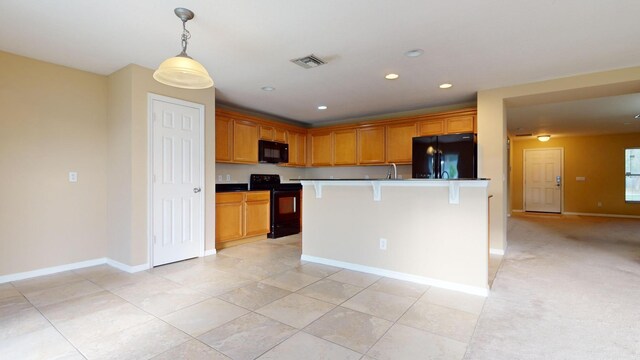 kitchen with a breakfast bar, sink, light carpet, an island with sink, and black appliances