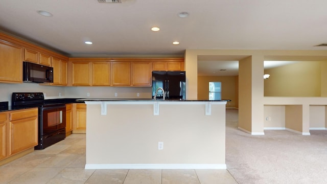 kitchen with a breakfast bar area, an island with sink, black appliances, and recessed lighting