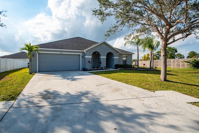 view of front of property with stucco siding, a front yard, fence, a garage, and driveway