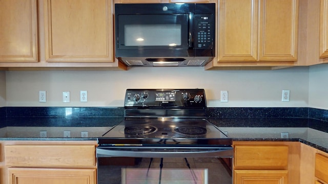 kitchen featuring dark stone countertops, built in desk, and black appliances