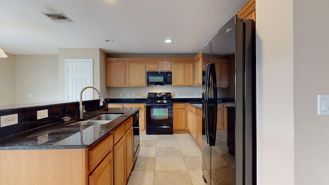 kitchen featuring sink, hanging light fixtures, light tile patterned floors, dark stone counters, and black appliances