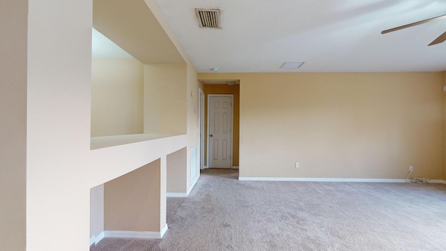 empty room featuring light carpet, a ceiling fan, visible vents, and baseboards